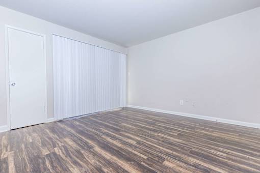 an empty room with wood flooring and white walls and doors