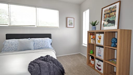 A bedroom with a white bed and a wooden bookshelf.