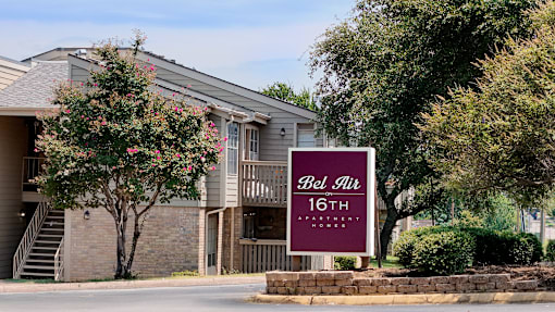 A sign for Bel Air Apartments stands in front of a building.