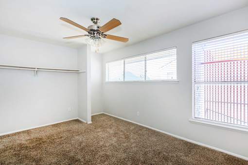 a bedroom with a ceiling fan and two windows