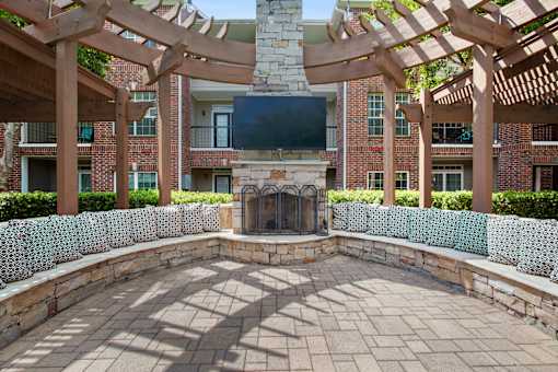 a patio with a stone fireplace and a large wooden structure