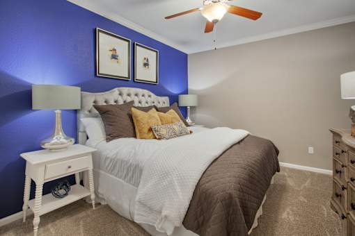 a bedroom with a bed and a blue wall and a ceiling fan