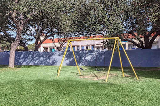 a yellow swing set in a playground with trees