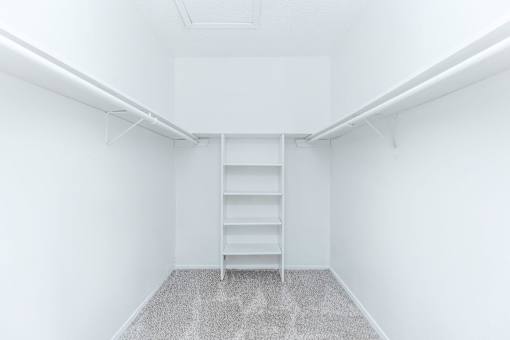 an empty room with white walls and a closet with shelves