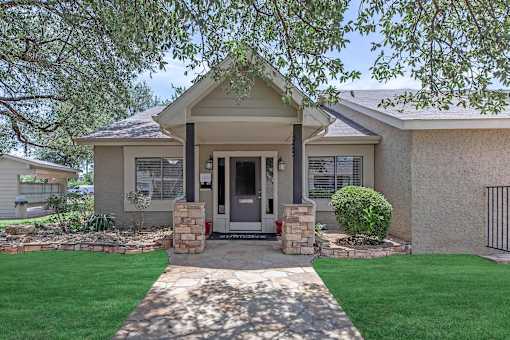 the front of a house with a walkway and grass