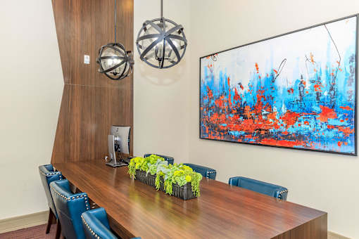 a conference room with a wooden table and chairs and a large painting on the wall