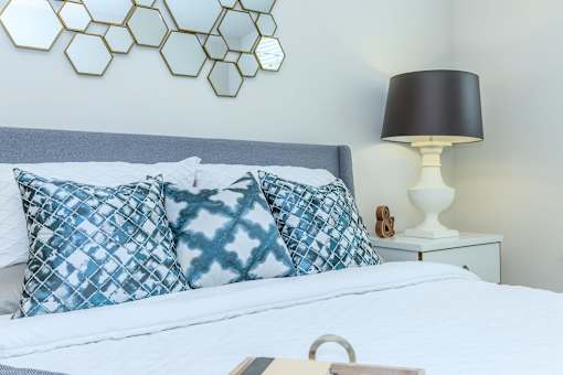 a bedroom with a bed with blue and white pillows   and a lamp