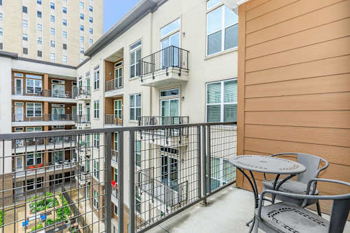 a balcony with a table and chairs and a building in the background