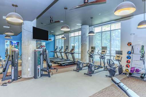 a gym with treadmills and other exercise equipment and windows