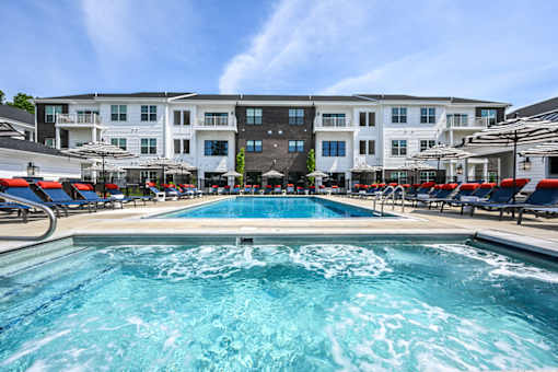 A large swimming pool in front of a multi-story apartment building.