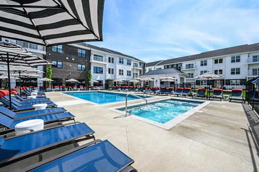 A sunny day at the pool with blue lounge chairs and umbrellas.