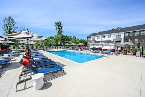 A pool area with sun loungers and umbrellas.