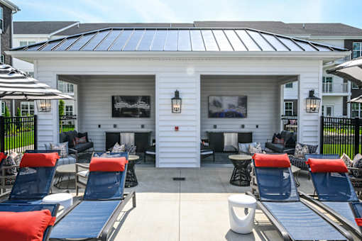 A white building with a black roof and a black screen door is surrounded by blue chairs.