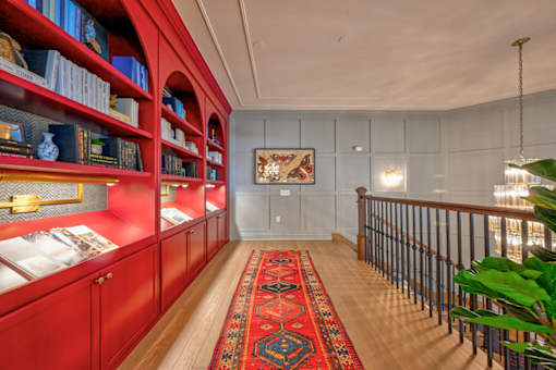 A room with red bookshelves and a rug on the floor.