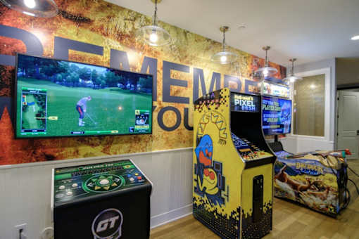 A room with a wall mural that says "Golf" and a row of arcade games.