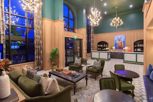 A living room with a green couch and a chandelier.