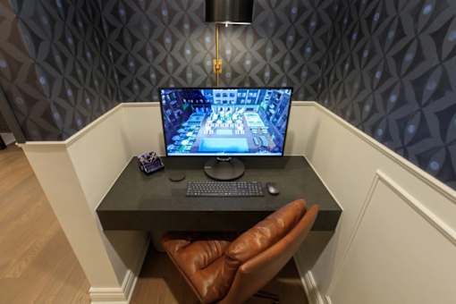 A brown leather chair is positioned in front of a desk with a laptop and a mouse on it.