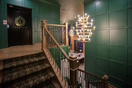 A staircase with a wooden handrail and a green wall.