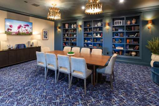 A room with a blue carpet and a wooden table with chairs.