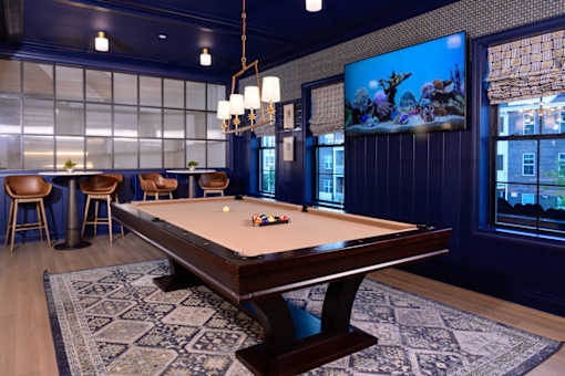 A pool table is in the middle of a room with a blue wall and a television.