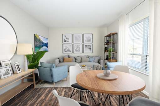 A living room with a grey couch, a wooden table, and a painting on the wall at Essex, Columbus, OH