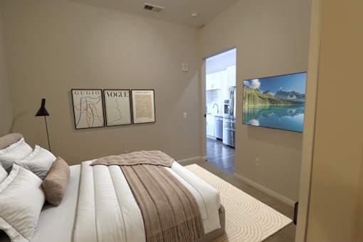 A bedroom with a bed, pillows, a blanket, a lamp, a framed picture on the wall, and a television at Essex, Columbus, OH