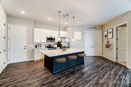 a kitchen with white cabinets and a blue island with three stools at Essex, Columbus, OH