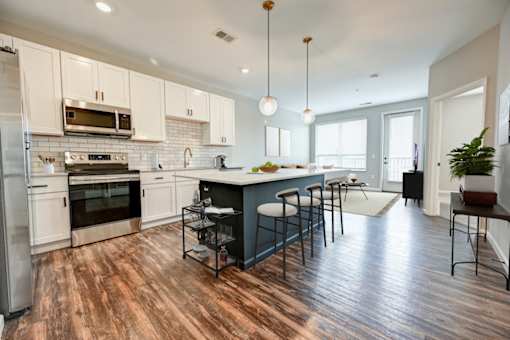 A kitchen with a wooden floor and white cabinets at Essex, Columbus, OH
