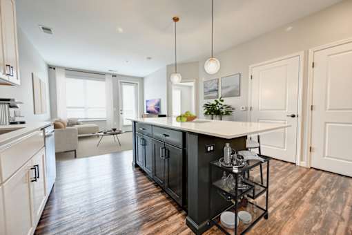 A modern kitchen with dark wood floors and white cabinetry at Essex, Columbus, OH