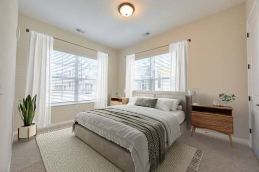 A bedroom with a large bed, a nightstand, and a window with white curtains.