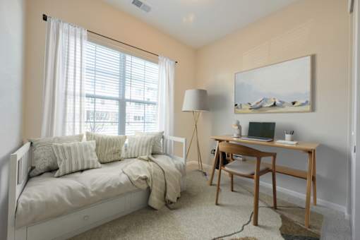 A bedroom with a bed, desk, and chair.