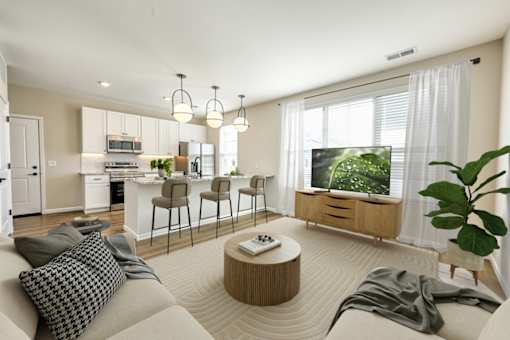 A modern living room with a grey sofa, a wooden coffee table, and a large window with a view of greenery outside.