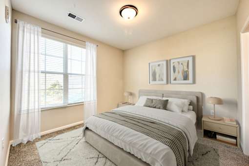 A bedroom with a large bed and a window with curtains.