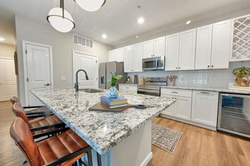 A kitchen with a marble countertop and white cabinets.
