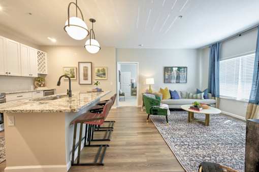 A modern kitchen with a bar and a living room with a sofa.