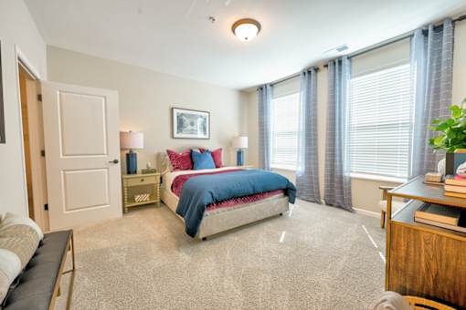 A bedroom with a bed, nightstand, and window.