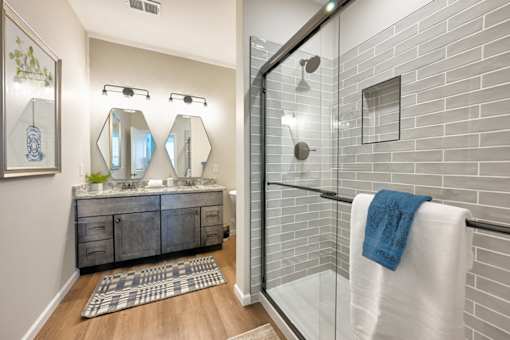 A bathroom with a white towel hanging on the glass shower door.