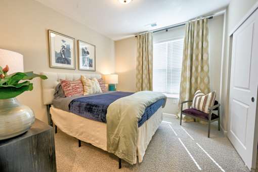 A bedroom with a bed, chair, and two pictures on the wall.