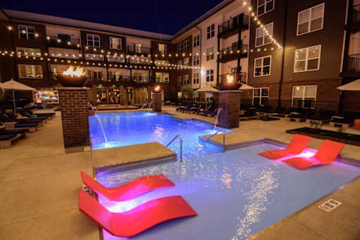 the pool is lit up at night with red chairs at Taylor House Apartments, Columbus, Ohio