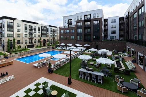 A large outdoor pool area with a grassy lawn and a black umbrella.