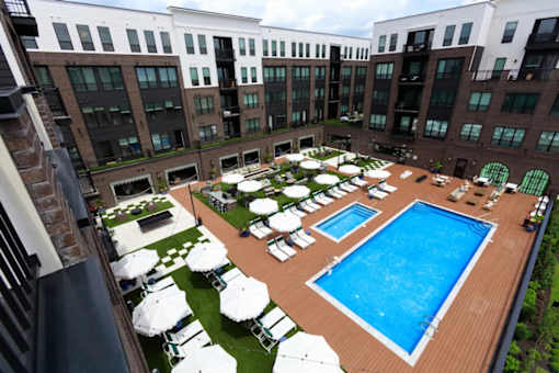 A large outdoor pool surrounded by sun loungers and umbrellas.