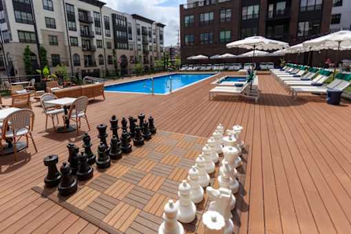 A giant chess set is set up on a wooden deck.