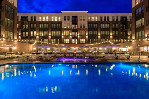 A large building with a pool in front of it at night.