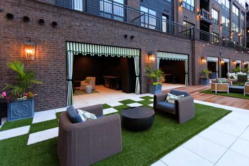 A patio area with a white and green striped awning over a table and chairs.