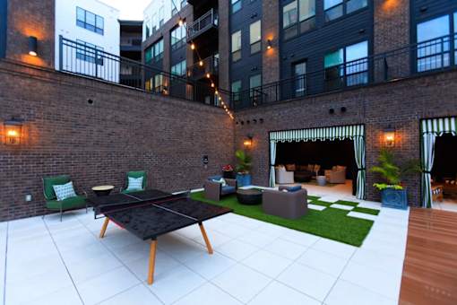 A black table is in the middle of a white tiled patio.