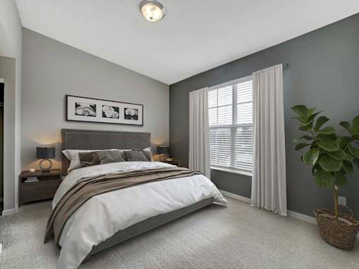 A bedroom with a large bed and a potted plant.