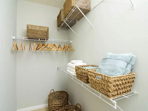 A white shelf with baskets and towels on it.