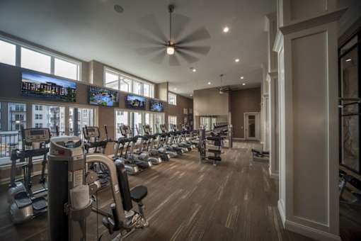A gym with a variety of equipment including treadmills, stationary bikes, and weight machines.