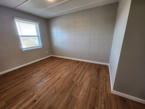an empty room with wooden floors and a window