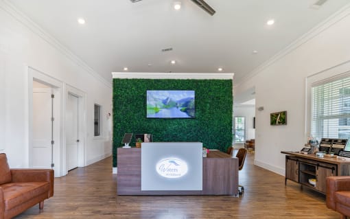 a reception area with a desk and a green wall with a tv on it